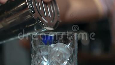 年轻的酒吧老板在时尚酒吧的酒吧里把饮料倒进玻璃杯里。